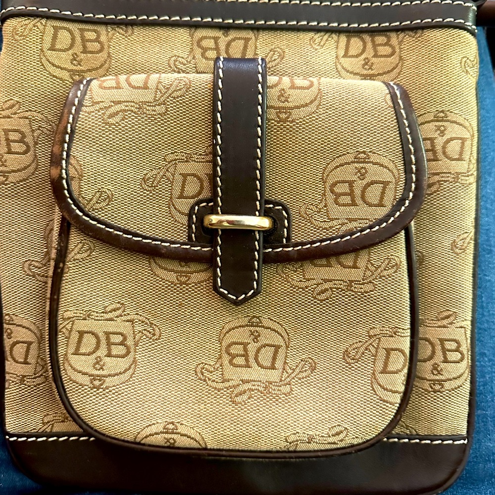 Dooney Burke cross body Dark Brown lettering on top of light brown back drop.